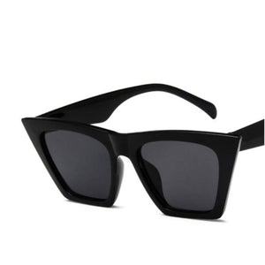 Black frame sunglasses in a stretched square design that is wider from the top part of the frame and smaller from the bottom, with a dark tinted lens. 