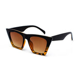 Sunglasses that are black from the top part of the frame and have a leopard skin black and orange pattern at the bottom of the frame, The shape is square but stretched out towards the top. The lens is a light orange tint.