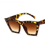  These sunglasses have a leopard skin finish from the top part of the frame to the bottom, including the handle. The shape is square but stretched out towards the top. The lens is a light brown gradient from a top to bottom tint.