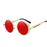 Stylish sunglasses with a red lens and a gold rounded frame. The edges of the frames are extended by a small stylish bezel to cover the top and bottom of the eyes. With a spring attached across to the lower part of the handles.
