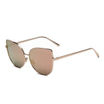 A pair of cat-eye styled sunglasses with a pointy corner at the top right and left with a circular design frame. A smooth round edge with a strong, sturdy gold finish around the lens. The lens is a shade of pastel pink.
