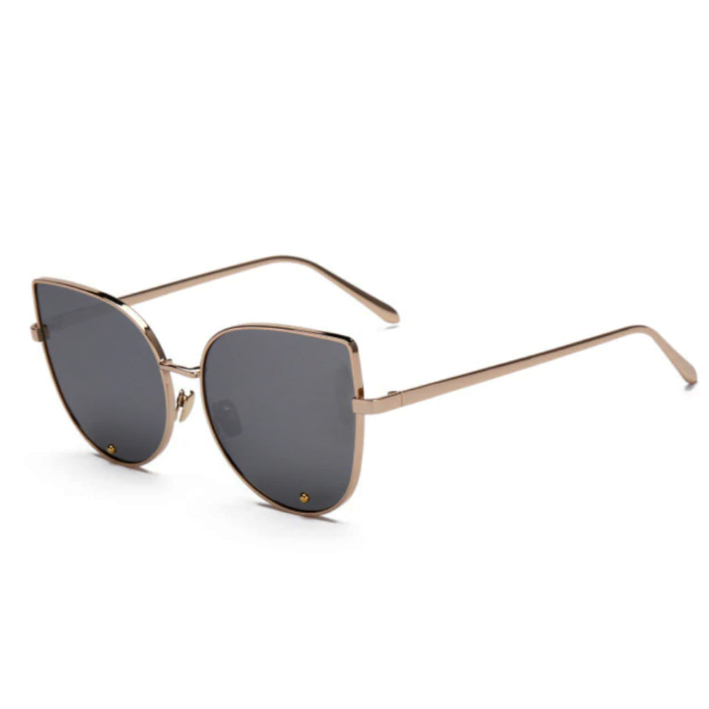A pair of cat-eye styled sunglasses with a pointy corner at the top right and left with a circular design frame. A smooth round edge with a strong, sturdy golden brown finish around the lens. The lens is a shade of silver.