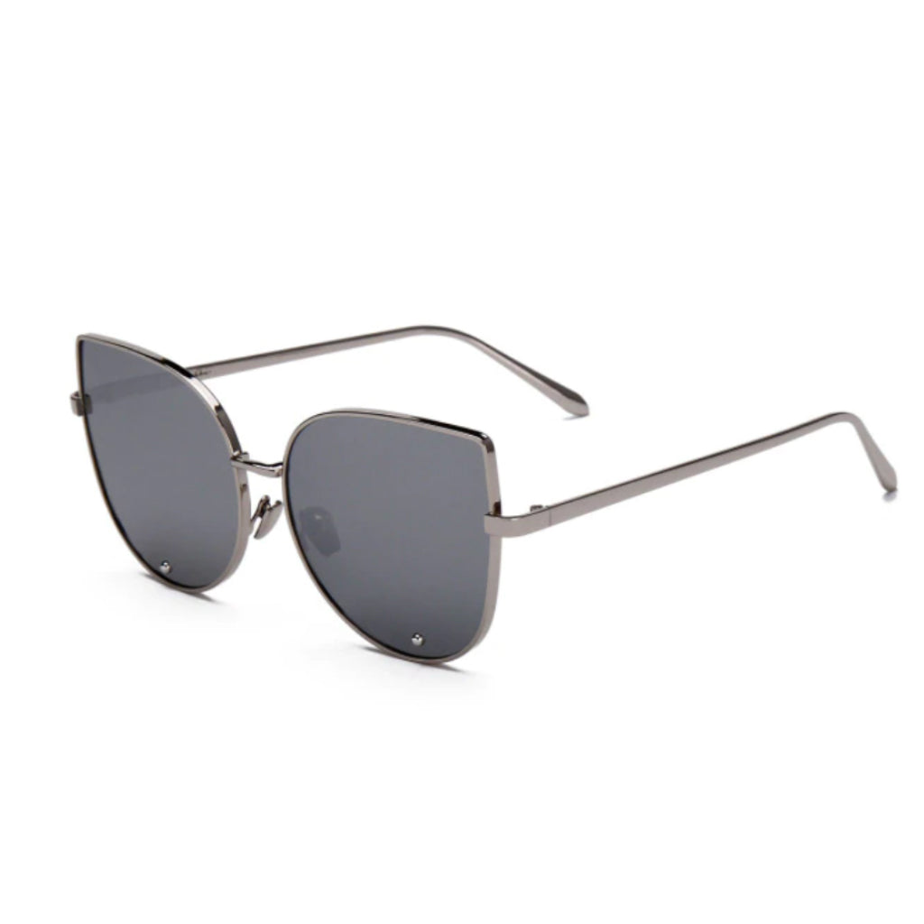 A pair of cat-eye styled sunglasses with a pointy corner at the top right and left with a circular design frame. A smooth round edge with a strong, sturdy silver finish around the lens. The lens is a tint of silver.