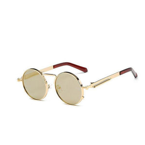 A round pair of sunglasses with a gold ring-shaped frame around the lens. With a thin design around the handles and a thin line between the top lens. The lens is a shade of gold.