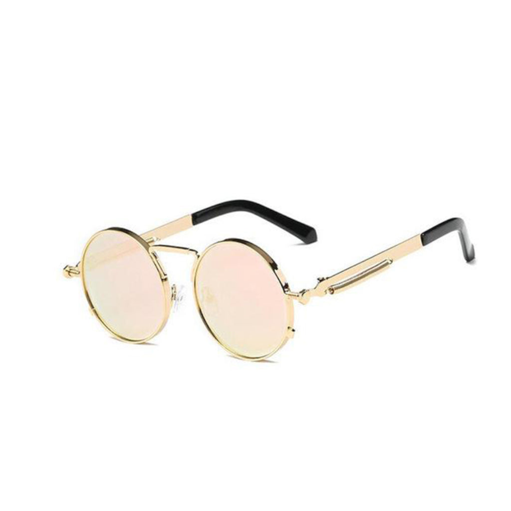 A round pair of sunglasses with a gold ring-shaped frame around the lens. With a thin design around the handles and a thin line between the top lens. The lens is a shade of pink.